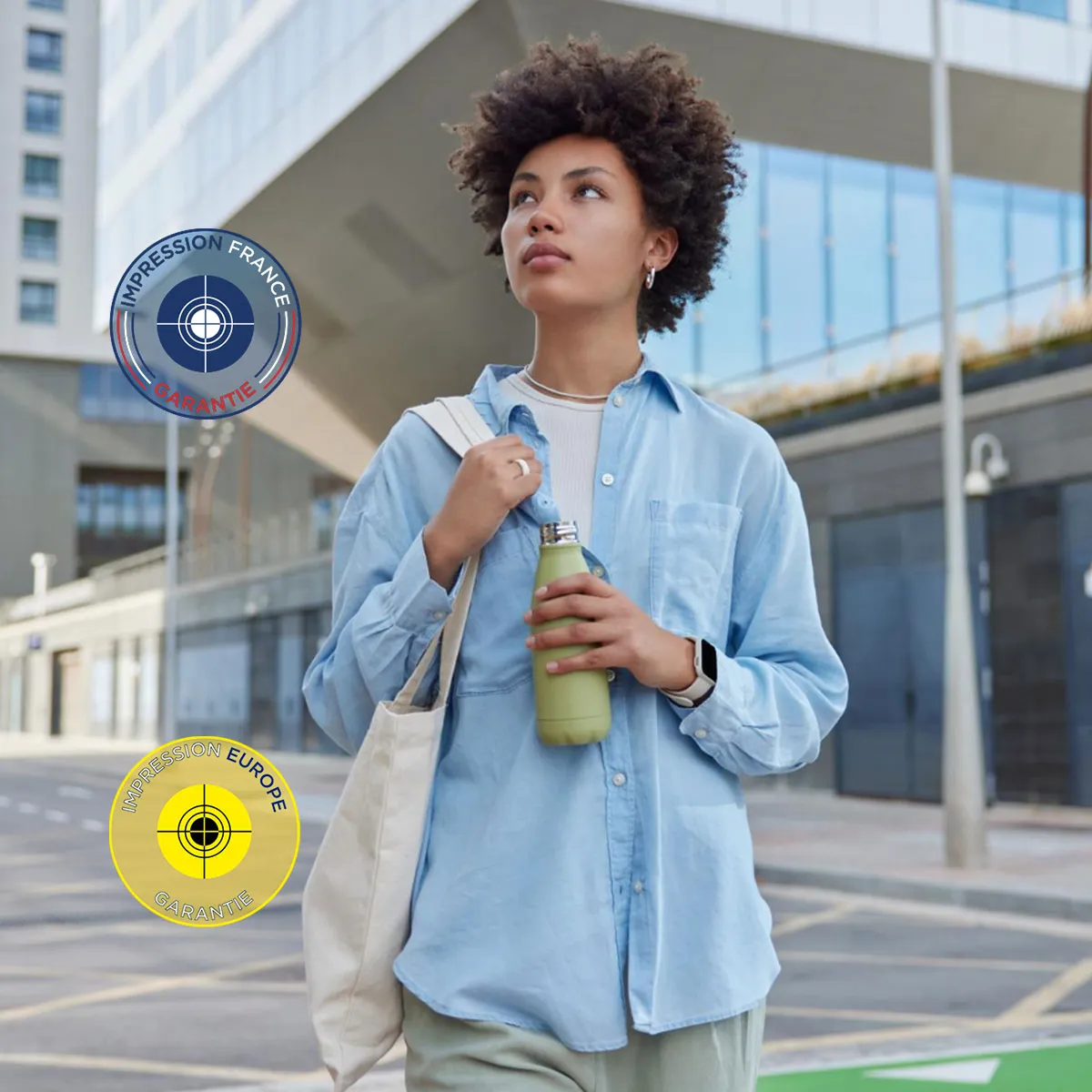 votre-idée-est-notre-quotidien Jeune femme tenant une gourde verte et un tote bag, marchant en ville, entourée des logos 'Impression France Garantie' et 'Impression Europe Garantie'.